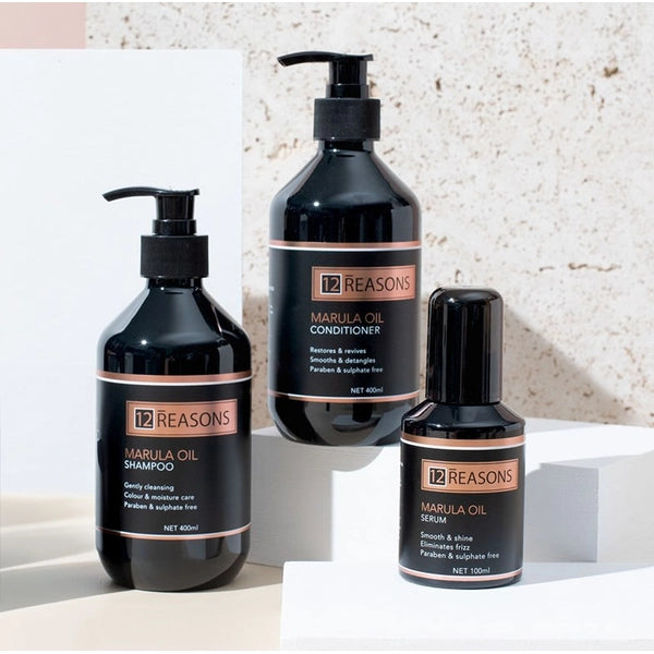 12 Reasons Marula Oil shampoo, conditioner and serum on white pedestals